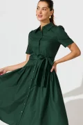 Model posing in a dark green button-down dress with a tied waist, against a light background.