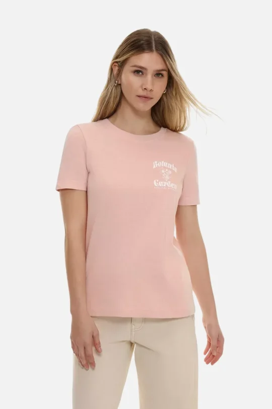 Woman wearing a light pink short-sleeve tee with a small white “Botanical Garden” print on the chest, paired with beige pants.
