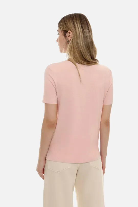 Back view of a woman wearing a light pink short-sleeve T-shirt and beige pants, with middle-parted light brown hair.