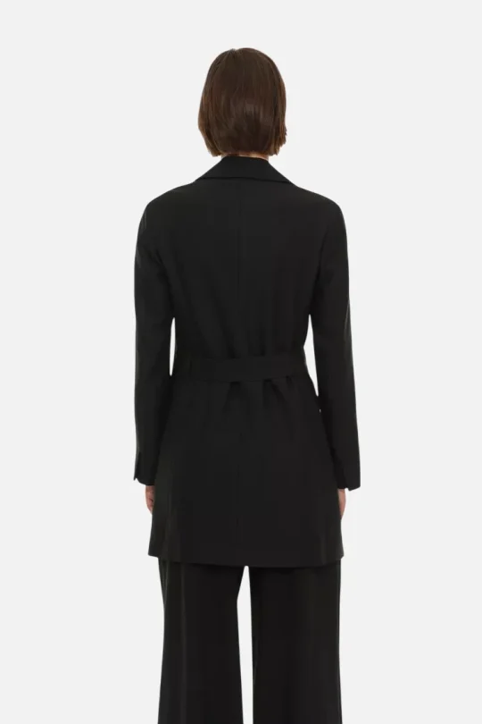 Back view of a woman wearing a black belted blazer and matching wide-leg pants, seen from the rear.
