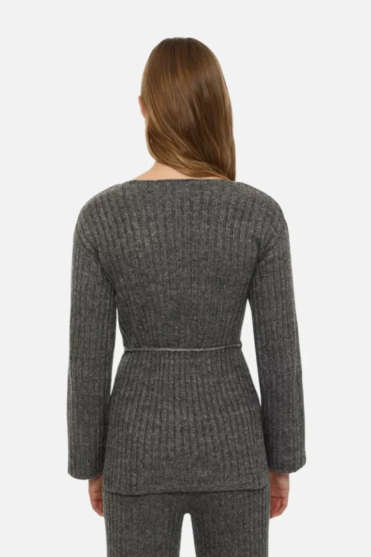Back view of a person wearing a dark gray ribbed knit cardigan with a slim belt at the waist and matching pants.